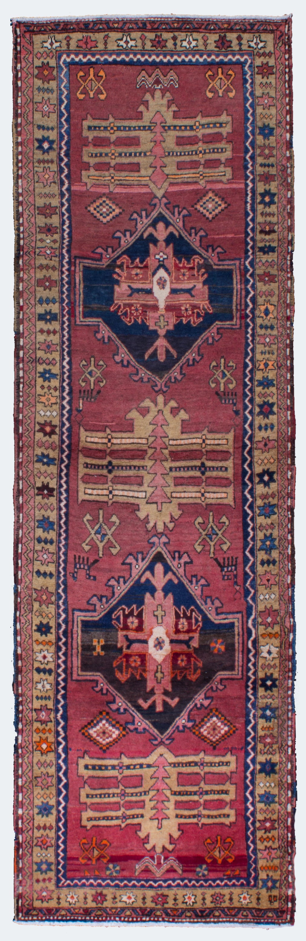 this is a Persian Vintage Rug Runner with the hue of rose color and pine tree in the middle line and colors of blue and pink and some oranges. it is perfect runner to glow in any spaces